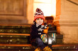 Little cute kid boy with with a light lantern on stairs near church.