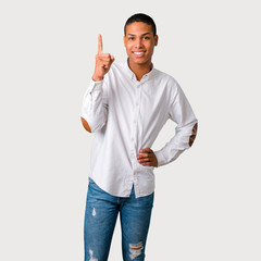 Young african american man showing and lifting a finger in sign of the best on grey background