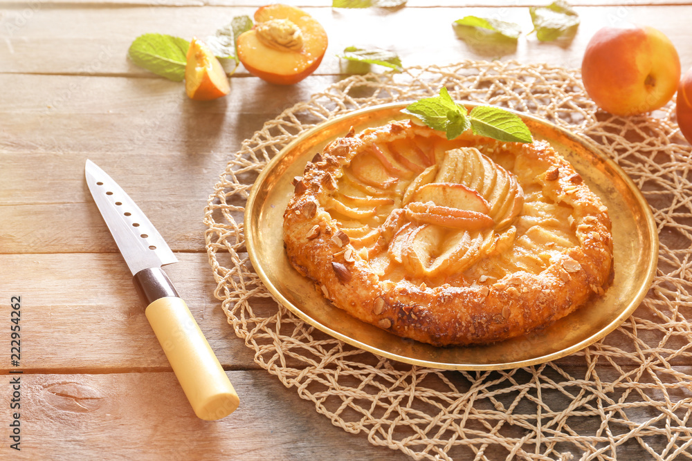 Plate with delicious peach galette on wooden table