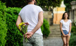 © be free - Man hides flower bouquet behind back while waits girl romantic date. Guy prepared surprise for girlfriend. First impression always important. Surprise for her. Couple meeting for date park background