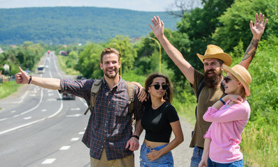 Wall Mural - Friends hitchhikers looking for transportation sunny day. Family weekend. Company friends strats adventure with hitchhiking. Company friends travelers hitchhiking at edge road nature background