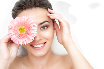 Portrait of cute beauty female woman adult with clean pure skin with pink flower taking spa relaxing in bath with white soap shampoo water. Skin beauty health care concept. Body part bare shoulder