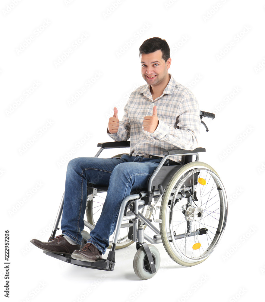 Young man in wheelchair showing thumb-ups gesture on white background
