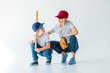 © LIGHTFIELD STUDIOS - mommy and son squatting with baseball bat and glove on white and looking at each other