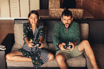 Wall Mural - Young Couple Playing Video Game Together at Home