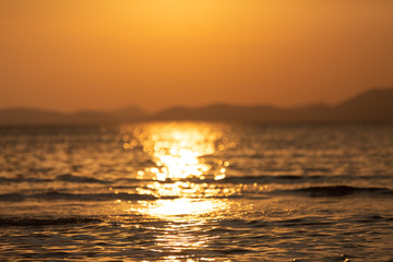 Beautiful summer golden sunset above the sea with calm waves and reflection of the sun