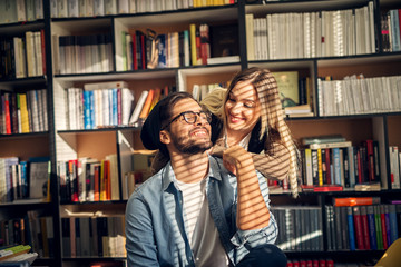 Wall Mural - Happy beautiful smiling hipster couple studying together in library.