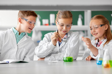 Poster - education, science, chemistry and children concept - kids or students with test tube making experiment at school laboratory