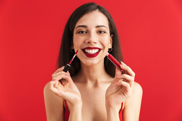 Wall Mural - Excited woman posing isolated holding lip gloss doing makeup.