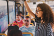 © dusanpetkovic1 - Serious young curly girl standing in a bus full of people.