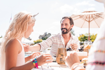 Family vacation. Delighted joyful man smiling to his daughter while sitting at the table with her