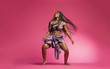 © Paul - Beautiful African Black girl wearing traditional colorful African outfit does a dramatic dance move against a colorful pink background