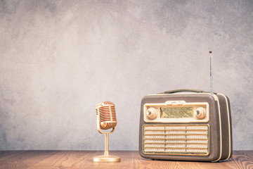 Poster - Retro portable broadcast radio receiver with leather case design from circa 1950s and golden microphone front textured concrete wall background.  Listen music concept. Vintage old style filtered photo