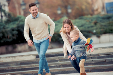 Wall Mural - Smiling young parents and their child in city