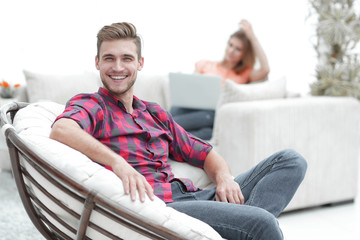 Wall Mural - smiling young male sitting in a big chair