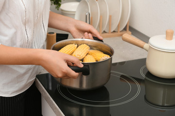 Sticker - Woman preparing corn in stewpot on stove, closeup