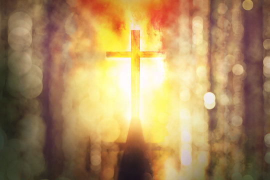 silhouette of burning cross with rays of sunlight background