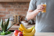 © golubovy - healthy morning tradition of freshly squeezed fruit juice. unrecognizable man holding a glass of natural organic banana and nectarine beverage. balanced diet and nutrition.
