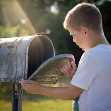 Closeup Of Cute Boy Opening A Post Box And Checking Mail. Kid Waiting For A Letter, Checking Correspondence And Looking Into The Metal Mailbox.