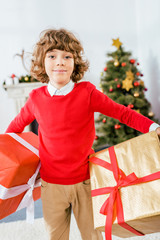 cute happy kid holding big christmas boxes and looking at camera