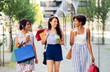 © Syda Productions - sale, consumerism and people concept - happy young women with shopping bags and drinks walking along city street