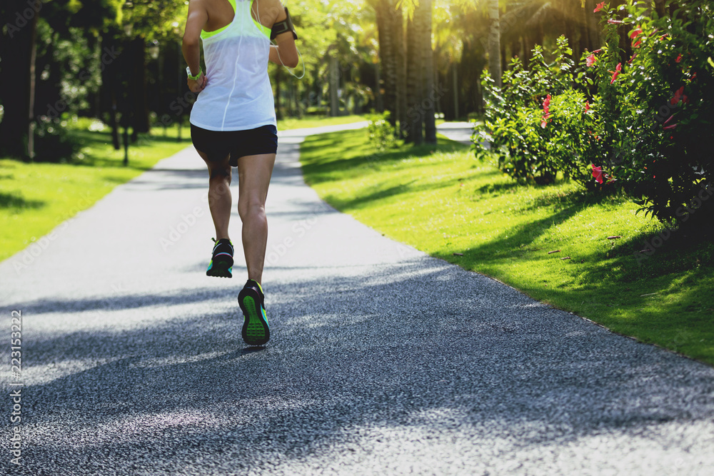 sporty fitness woman running at sunny park