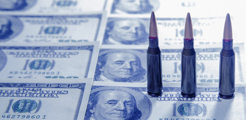 Bullets against US Dollar bills background as an abstract symbol of business, military conflicts and murders.