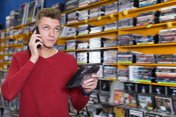 Smiling guy talking on mobile phone in shop