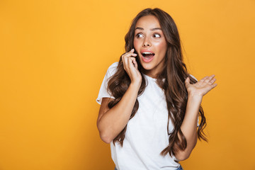 Wall Mural - Portrait of european woman 20s with long hair shouting and talking on mobile phone, isolated over yellow background