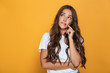© Drobot Dean - Image of beautiful woman 20s with long hair looking aside at copyspace, isolated over yellow background