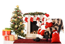 Santa Claus With Letter Sitting In Armchair Near Fireplace And Christmas Tree Isolated On White