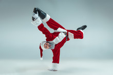 Funny Serious Guy With Christmas Hat Dancing At Studio. New Year Holiday. Christmas, X-mas, Winter, Gifts Concept. Man Wearing Santa Claus Costume On Gray. Copy Space. Winter Sales.