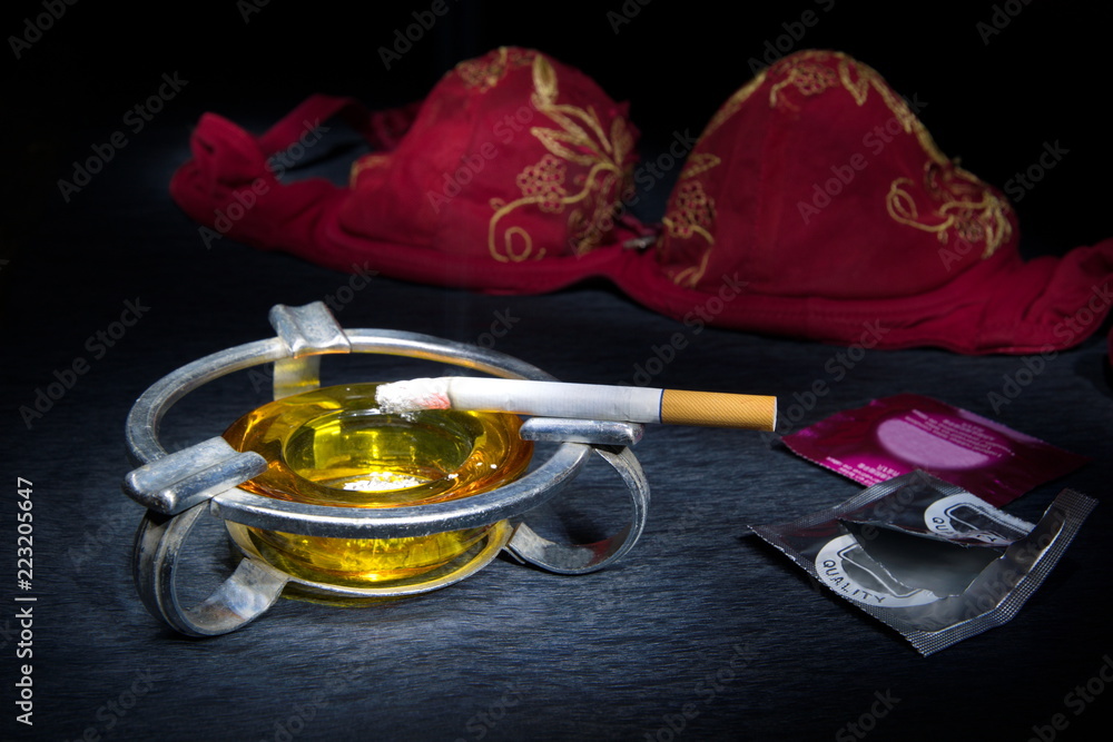 Cigarette after sex.Bras and condom.Satisfaction Stock Photo