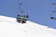 © Olga - White snow-capped mountain slopes with skiers and a ski lift with skiers