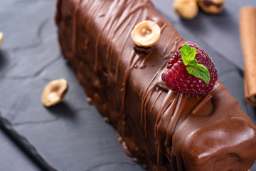 Wall Mural - Closeup of caramel chocolate dessert with hazelnuts. Served with cinnamon, raspberries and mint on black background.