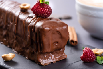 Wall Mural - Caramel chocolate cake with hazelnuts. Served with cinnamon, raspberries and mint on black background.