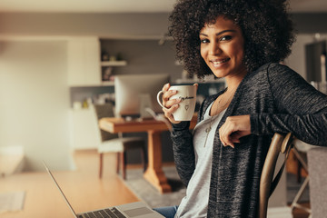 african woman taking coffee break while working from home