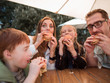 © ASDF - hungry family eating hamburgers, sitting at a table in a fast food restaurant