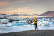 Young woman dressing cold clothes seeing the amazing Jokulsarlon, iceberg lagoon in Iceland