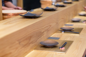 empty black ceramic dish on wooden bar, Omakase style Japanese.