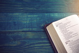 Fototapeta  - Holy Bible on a Blue Wooden Table Out for Studying