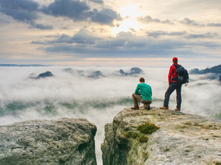 hiker and photo enthusiast stay on cliff. peak with two men