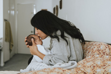 Wall Mural - loving mother kissing her infant baby