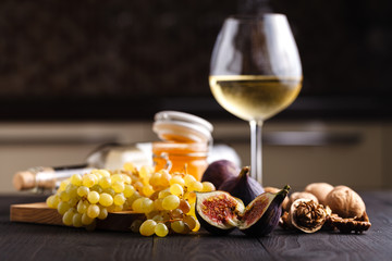 Grape, figs and honey with a glasses of  white wine on wood background