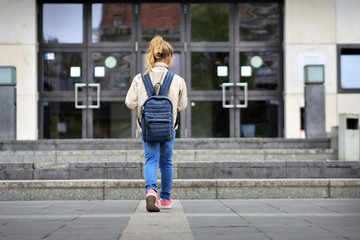 A child, turned of shoulders, it enters to school to his/her first day. Concept of: education, teaching, love for the school.