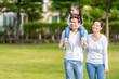 © Nattanon - Cute Asian girl on neck parents big happy laughing and run around together.Happy family piggybacking adorable little daughter is smiling.