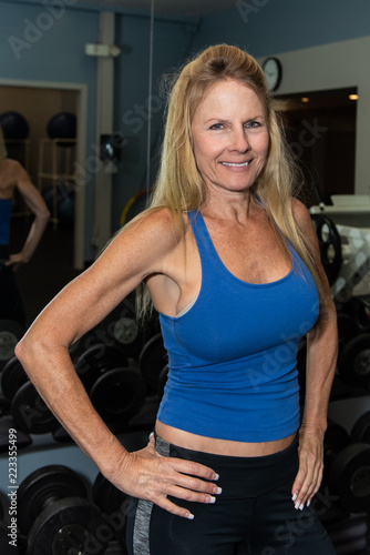 Fotografie, Obraz Smiling middle age female content with life while posing in health club weight room