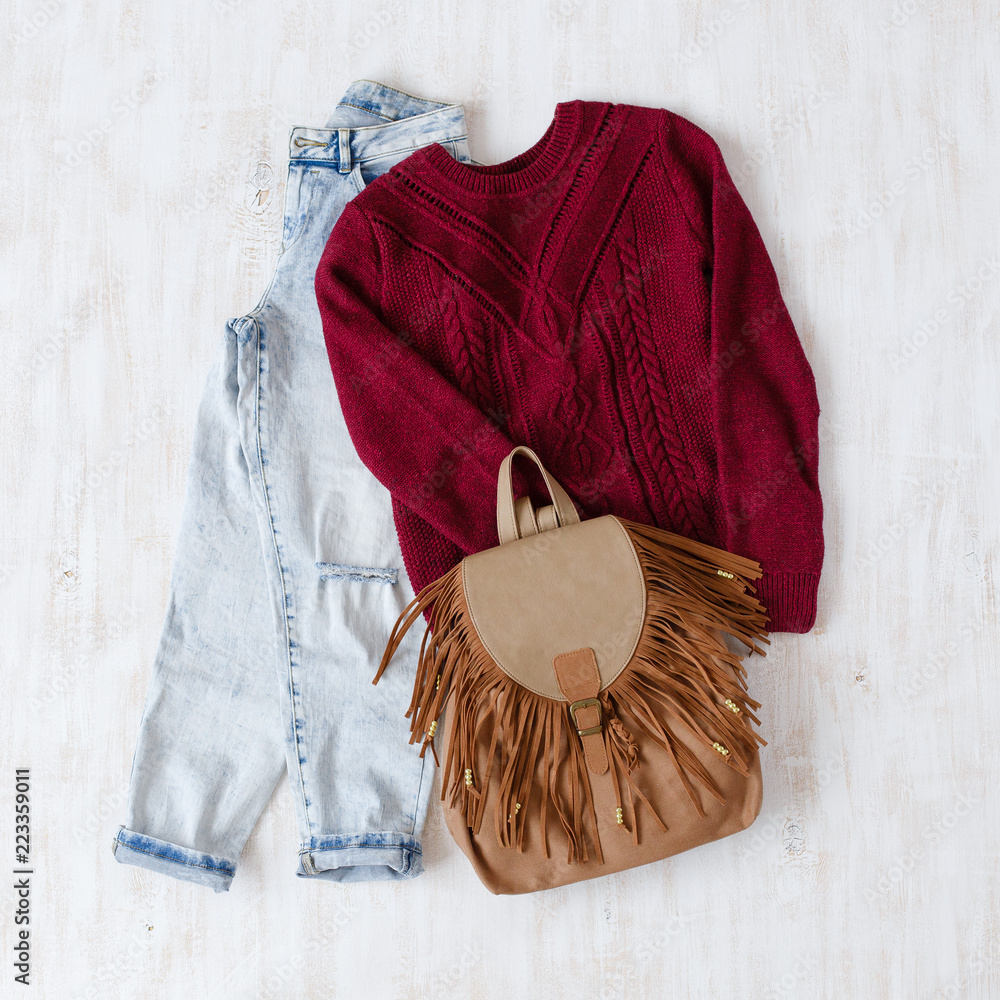 Light blue ripped boyfriend jeans, dark red oversize knitted sweater and  brown boho backpack with fringe on white wooden background. Overhead view  of woman's casual day outfits. Trendy hipster look. Stock Photo |, image size:1000x1000