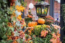 Autumn Outdoor Decorations. Orange Pumpkin And Retro Forged Lanterns With Maple Leaves,flowers And Hawthorn Berries In A Pavillion. Red Brick Building