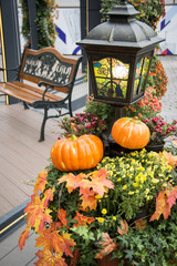 Wall Mural - Autumn outdoor decorations at the festival. Orange pumpkin and retro lantern with maple leaves,flowers and hawthorn berries. A bench metal forged in a pavilion